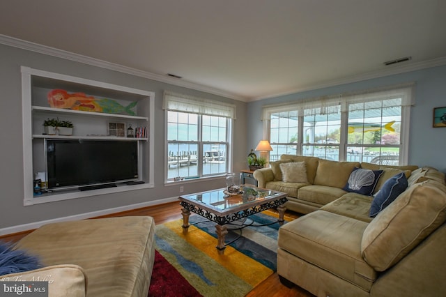 living area with visible vents, baseboards, crown molding, and wood finished floors