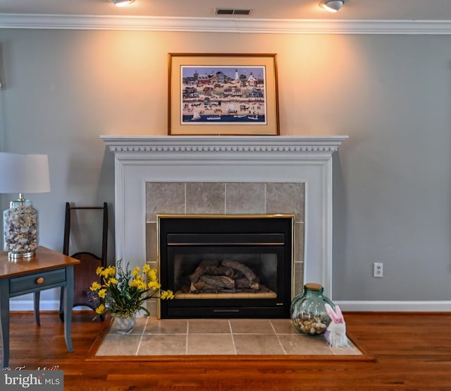 details with crown molding, wood finished floors, a fireplace, and visible vents