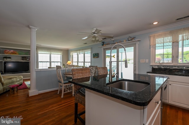 kitchen featuring dark stone countertops, dark wood finished floors, a sink, and ornamental molding