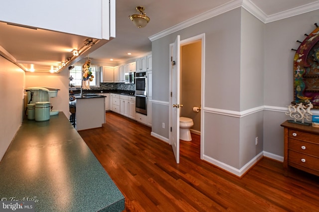 kitchen featuring crown molding, tasteful backsplash, dark wood-style flooring, dark countertops, and stainless steel appliances