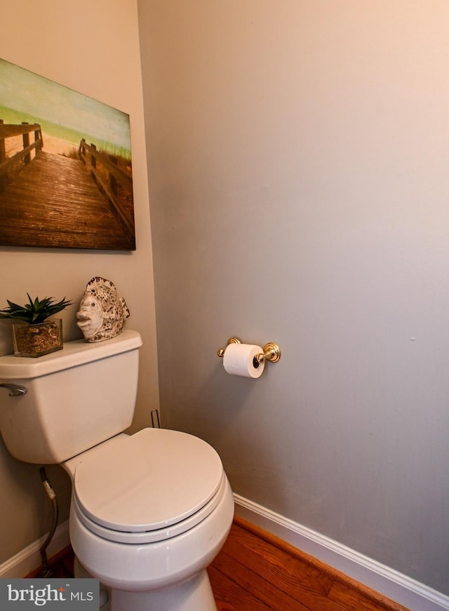 bathroom with toilet, baseboards, and wood finished floors