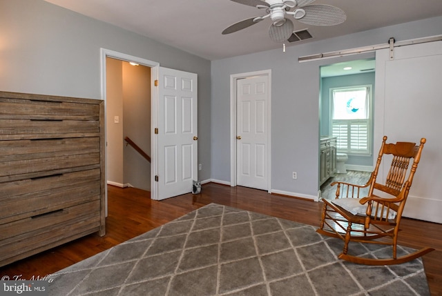 sitting room with visible vents, baseboards, a barn door, a ceiling fan, and wood finished floors