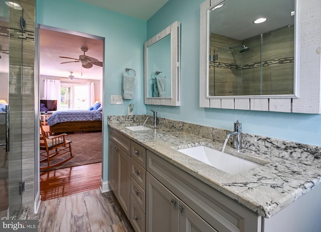 full bathroom featuring a stall shower, wood finished floors, double vanity, and a sink