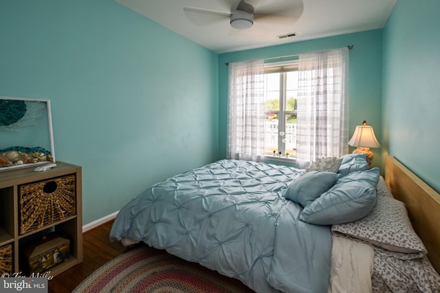 bedroom featuring wood finished floors, baseboards, a ceiling fan, and visible vents