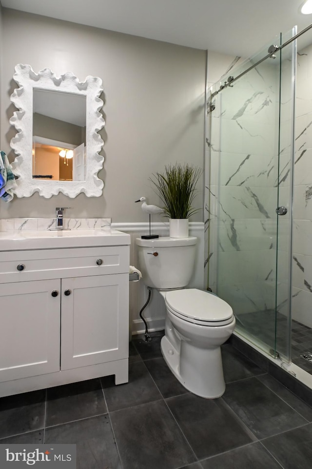 full bath featuring tile patterned floors, toilet, vanity, and a marble finish shower