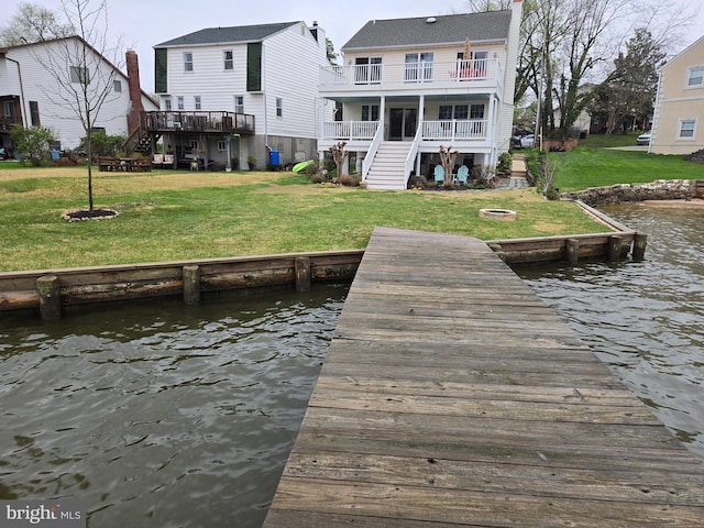 view of dock featuring a water view, stairway, a balcony, and a lawn