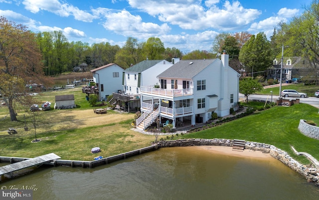 back of house with a yard, a balcony, a chimney, stairs, and a deck with water view