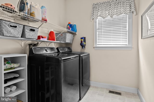 washroom featuring separate washer and dryer, baseboards, laundry area, and visible vents