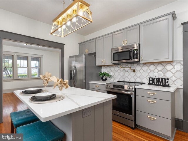 803 Berryville Ave, Winchester, VA 22601 - kitchen featuring gray cabinetry, a kitchen island, decorative backsplash, and appliances with stainless steel finishes