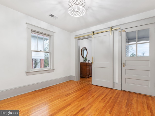 803 Berryville Ave, Winchester, VA 22601 - unfurnished bedroom with visible vents, light wood-style flooring, and a barn door