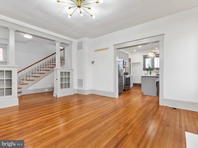 803 Berryville Ave, Winchester, VA 22601 - unfurnished living room featuring visible vents, a notable chandelier, light wood-style floors, and stairs