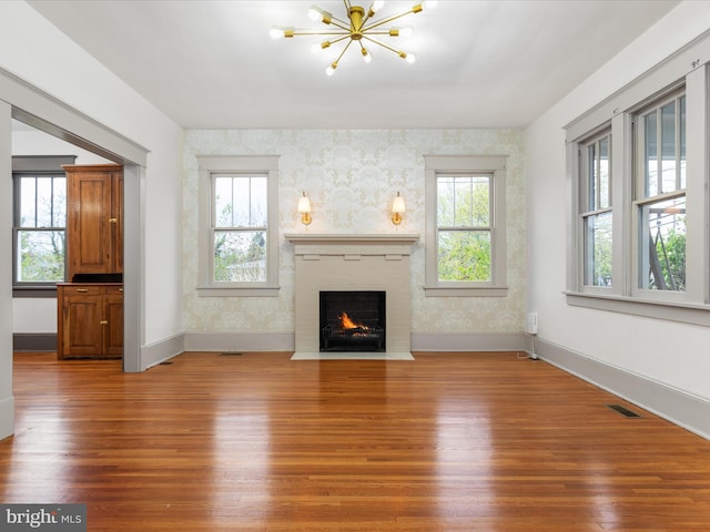 803 Berryville Ave, Winchester, VA 22601 - unfurnished living room with visible vents, a notable chandelier, wood finished floors, and a healthy amount of sunlight