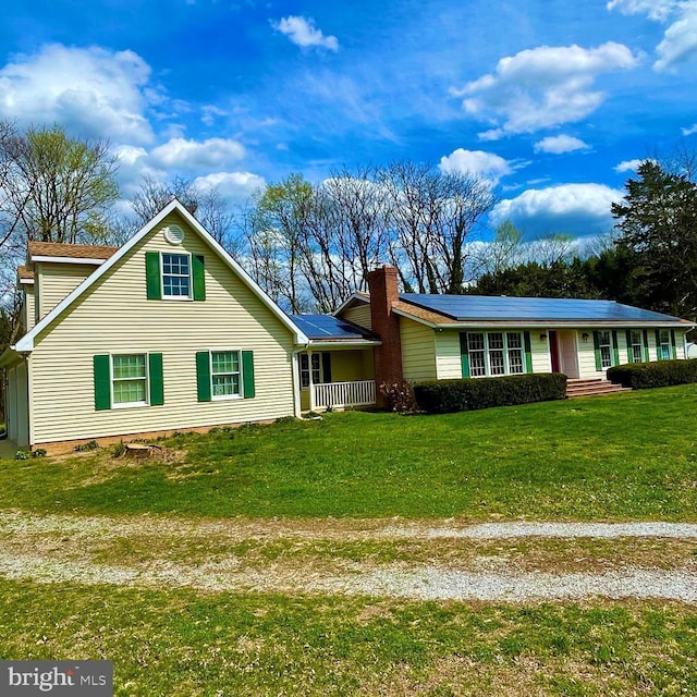 view of front of property featuring a front lawn, solar panels, and a chimney