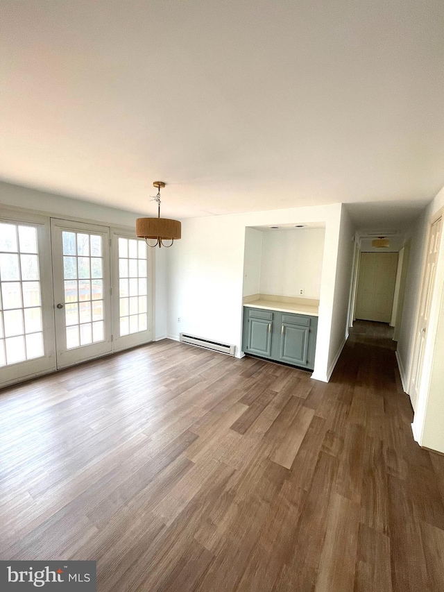 unfurnished living room featuring baseboard heating, an inviting chandelier, baseboards, and dark wood finished floors