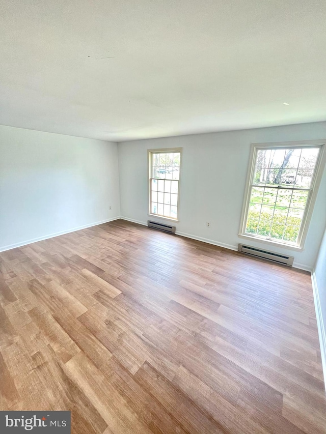 spare room featuring baseboard heating, wood finished floors, and baseboards