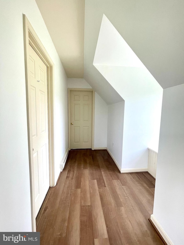 additional living space featuring baseboard heating, wood finished floors, baseboards, and vaulted ceiling