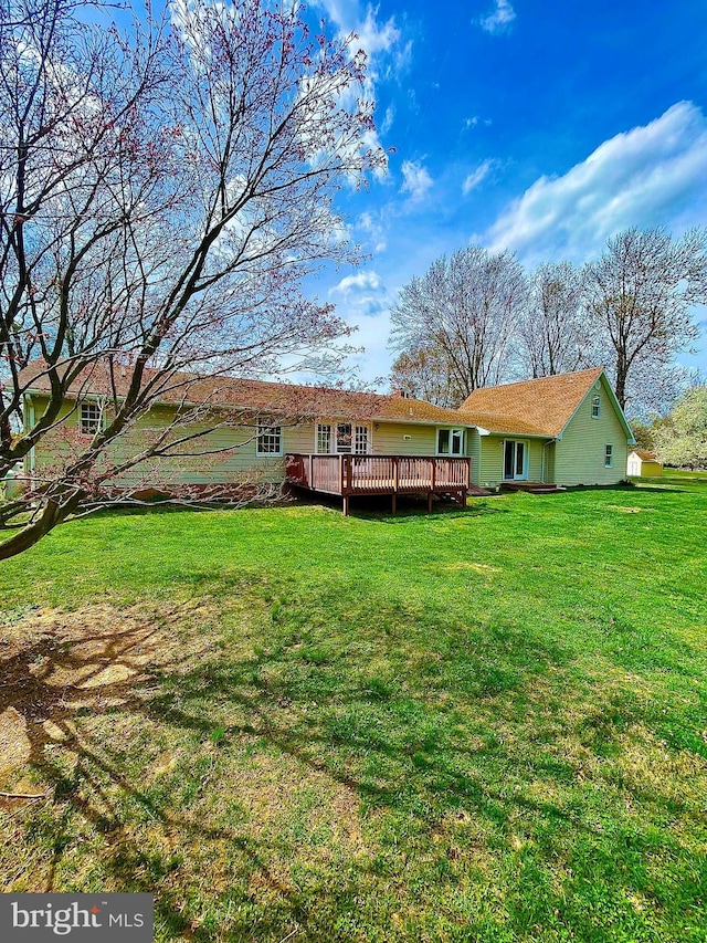 rear view of house featuring a wooden deck and a lawn