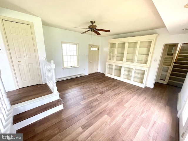 entryway featuring baseboards, a baseboard heating unit, a ceiling fan, stairs, and wood finished floors
