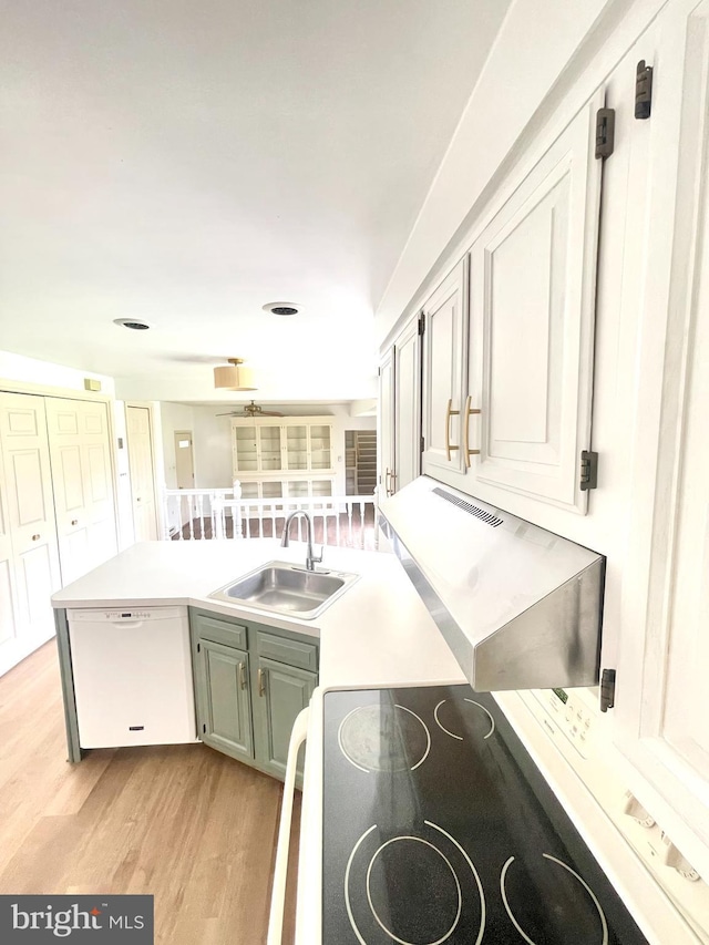 kitchen with light wood-style flooring, light countertops, electric range, white dishwasher, and a sink