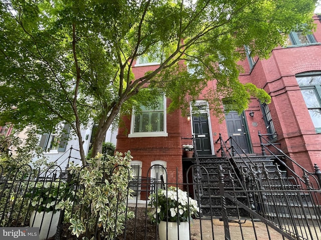view of front of house featuring brick siding and a fenced front yard