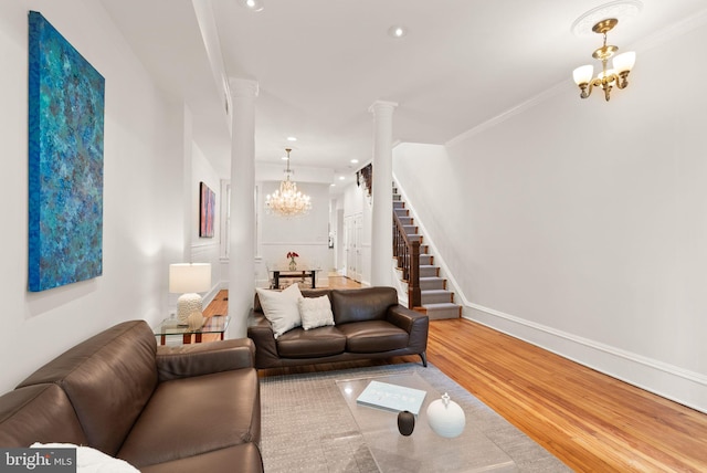 living area featuring stairway, recessed lighting, ornate columns, wood finished floors, and a notable chandelier