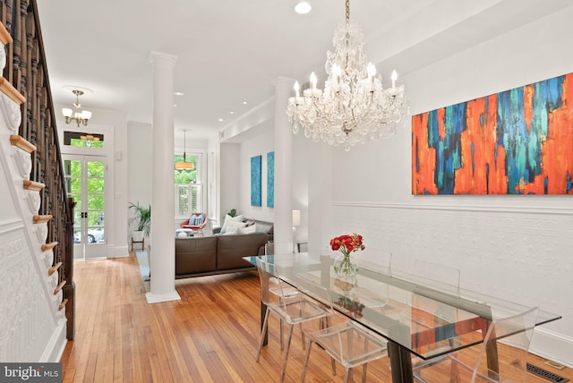 dining area featuring an inviting chandelier, hardwood / wood-style floors, ornate columns, and baseboards