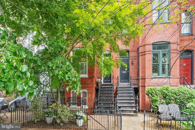 view of exterior entry featuring brick siding and fence