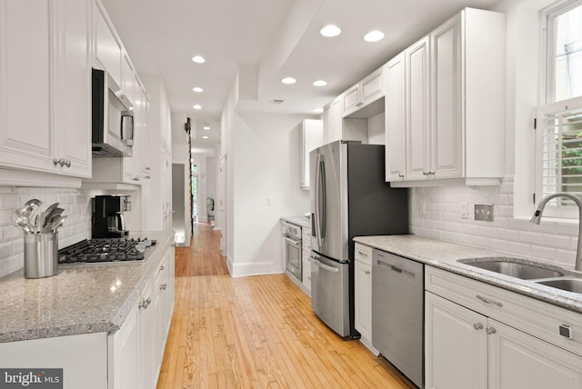 kitchen with a sink, appliances with stainless steel finishes, light wood-style floors, baseboards, and recessed lighting