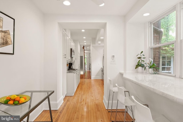 corridor with baseboards, light wood-type flooring, and recessed lighting