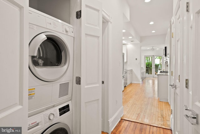 laundry area with stacked washer / dryer, light wood-style flooring, baseboards, recessed lighting, and laundry area