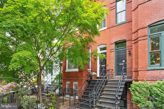 view of exterior entry with brick siding and fence