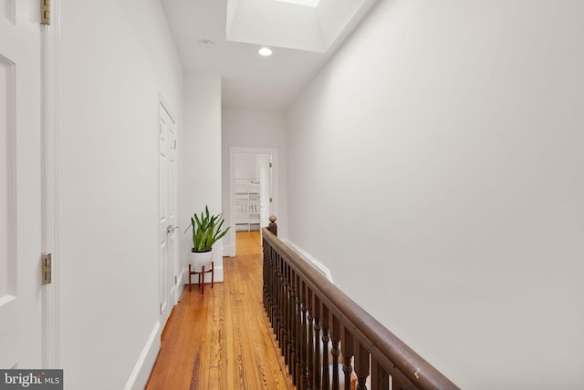 corridor with recessed lighting, a skylight, and light wood-style flooring