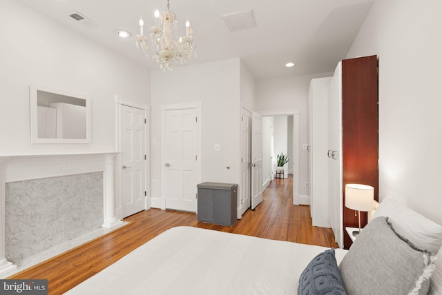 bedroom with visible vents, wood finished floors, a notable chandelier, and recessed lighting