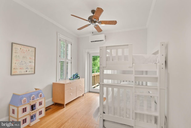 bedroom featuring a wall unit AC, light wood-style flooring, crown molding, access to exterior, and baseboards