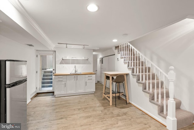 kitchen featuring wood counters, open shelves, light wood-style flooring, a sink, and freestanding refrigerator