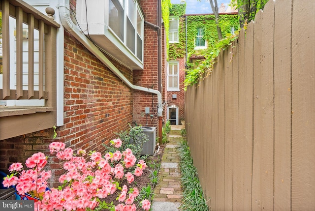 view of home's exterior featuring brick siding, fence, and central air condition unit