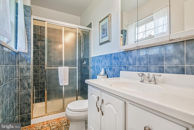 bathroom featuring vanity, toilet, a stall shower, and tile walls