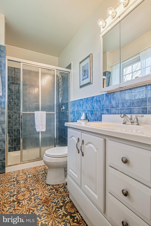 bathroom with a shower stall, vanity, tile walls, toilet, and tile patterned flooring