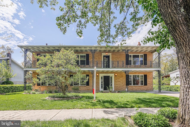 view of front of home with a front lawn, a balcony, and brick siding