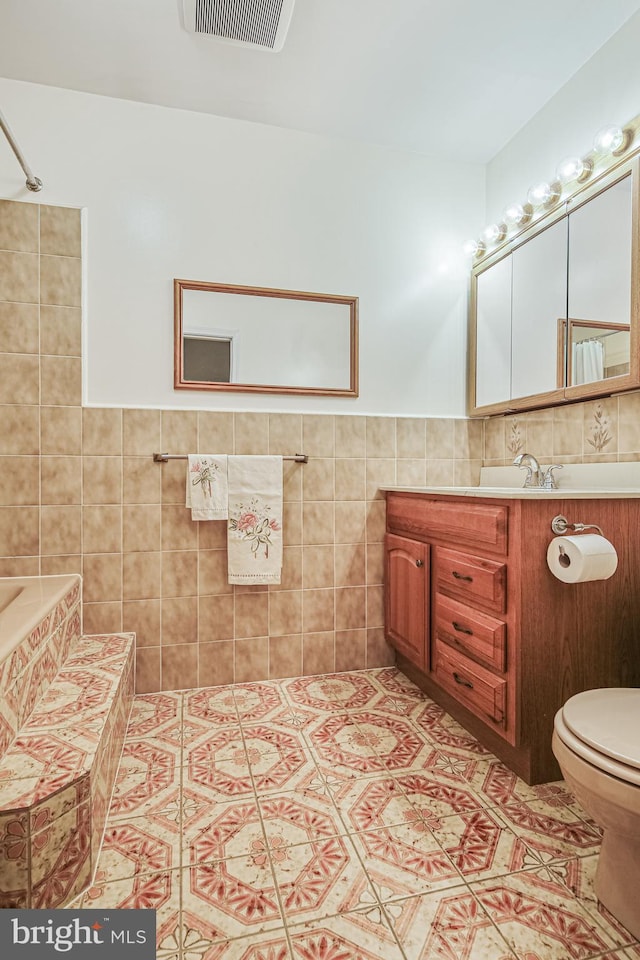 bathroom featuring toilet, tile patterned floors, visible vents, and tile walls