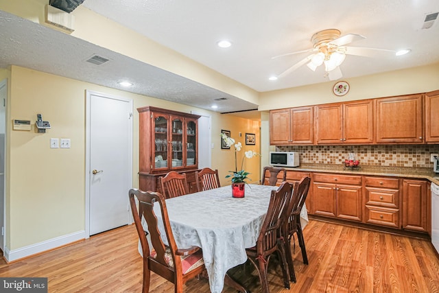 dining space featuring baseboards, light wood-style flooring, visible vents, and ceiling fan