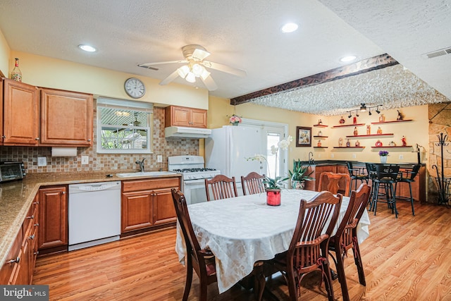 dining space with light wood-style flooring, visible vents, a textured ceiling, and a ceiling fan