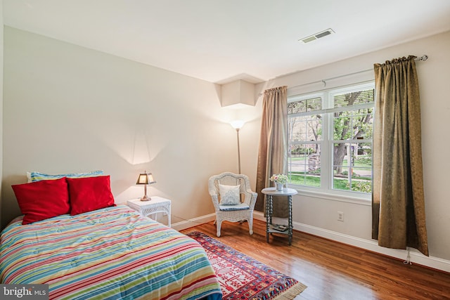 bedroom featuring wood finished floors, visible vents, and baseboards