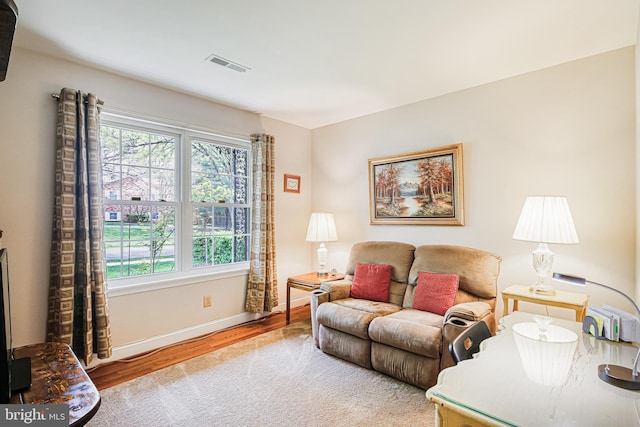 living area featuring wood finished floors, visible vents, baseboards, and a healthy amount of sunlight