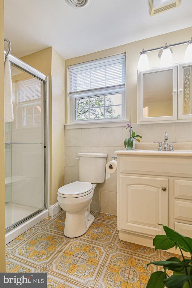 bathroom featuring tile patterned floors, visible vents, toilet, tile walls, and a stall shower