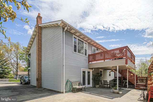 back of property featuring a chimney, a deck, french doors, a patio, and stairs