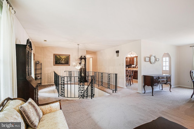 living area with baseboards, carpet flooring, arched walkways, and a notable chandelier