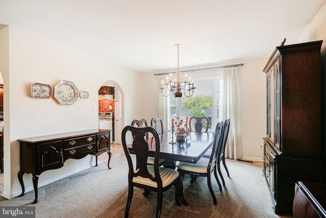 dining space featuring arched walkways, a notable chandelier, and light colored carpet