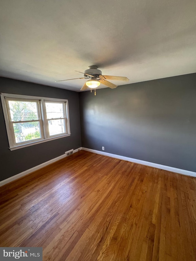 spare room with visible vents, baseboards, a ceiling fan, and wood finished floors