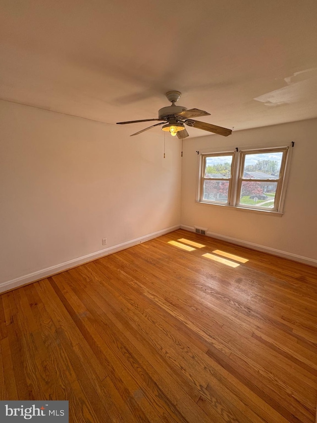 empty room featuring visible vents, baseboards, ceiling fan, and wood finished floors